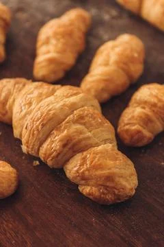 Vertical shot of an array of freshly baked, buttery croissants on a wooden table Stock Photos