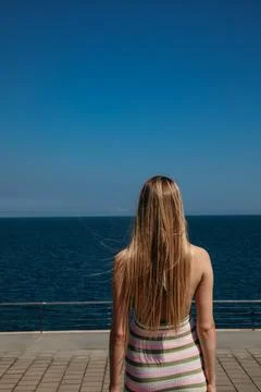 Vertical shot from back of long-haired girl walking on the beach in sunny day. . Fotos Stock