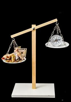 A vertical shot of a balancing scale balances money and compass with a pitch- Stock Photos