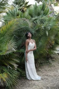 Vertical shot of beautiful Black young woman in a gold dress posing outdoor. Photos