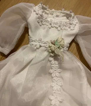 Vertical shot of a beautiful tiny white dress for a doll Stock Photos