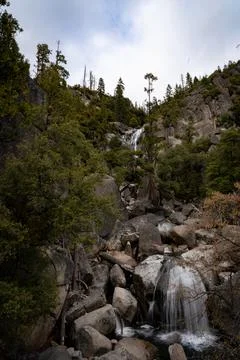 A vertical shot of a beautiful waterfall in a forest surrounded by cliffs and Stock-Fotos
