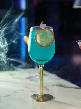 Vertical shot of a blue cocktail with dramatic smoke on a marble bar top 스톡 사진