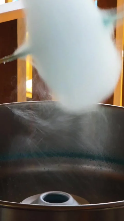 Vertical shot of blue cotton candy forming above spinning metal machine Stock Footage 316734810