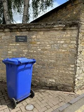 Vertical shot of a blue garbage bin in front of a brick wall Stock Photos
