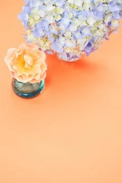 A vertical shot of blue hydrangea and polymer clay flower isolated on a peach Stock Photos