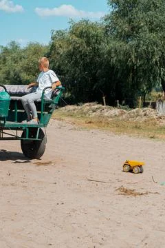 Vertical shot of a boy in a carriage pulling his toy truck by a string 写真素材