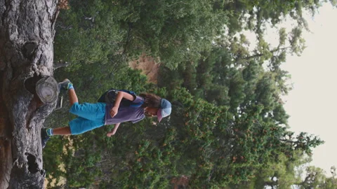 Vertical shot. boy walks on top of a fallen tree in the forest.  Stock Footage 249530722