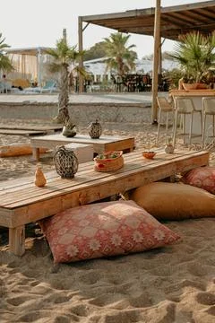 Vertical shot of a cafe on sand with pattern cushion and wooden table Fotos de archivo