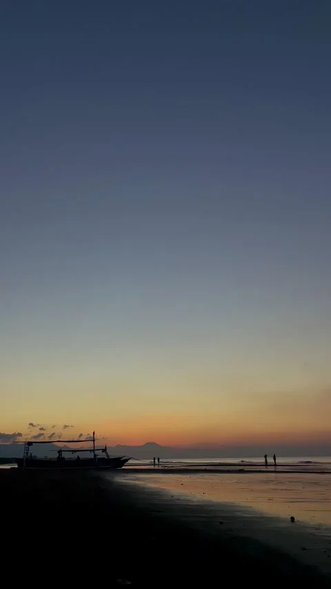 Vertical shot of calm beach dawn with boat silhouette and copy space Bali Video stock 343796748