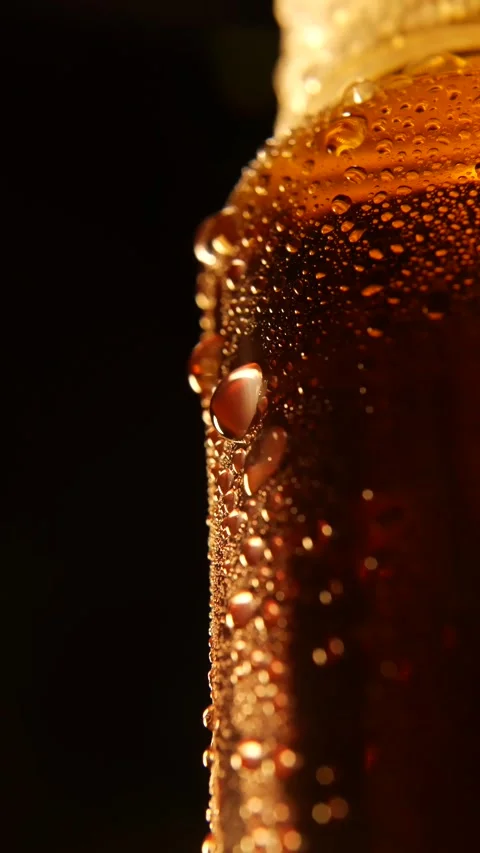 Vertical shot of a capped brown bottle glowing under warm light, surrounded by a Stock Footage 314664919