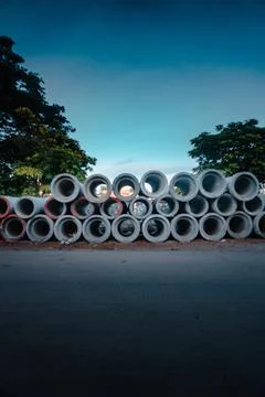 Vertical shot of cement tubes piled up on the side of a road 스톡 사진