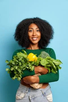 Vertical shot of charming curly haired woman keeps a variety of fresh vegetables Stock-Fotos