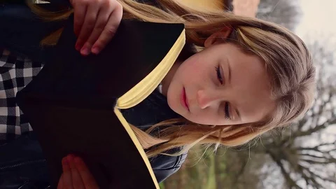Vertical shot of a charming smiling cheerful girl reading a textbook Stock-Footage 127714492
