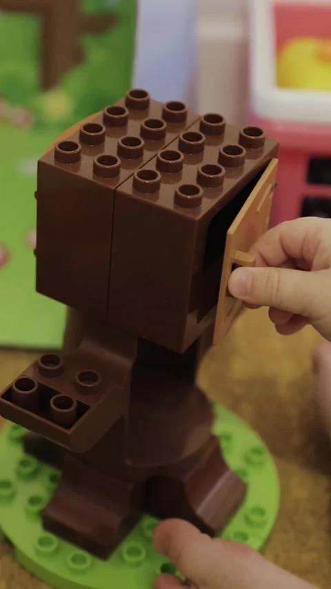 Vertical shot. Child builds a construction set sitting on the floor using Video stock 308455467