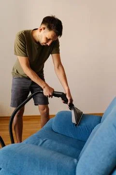 Vertical shot of cleaning worker in causal clothing using washing vacuum cleaner Stock Photos