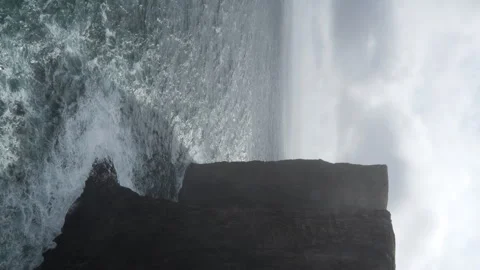 Vertical shot of cliff casting shadow on sea water on partly cloudy day, Stock Footage 286859172