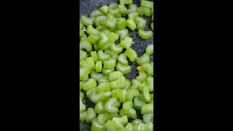 Vertical shot. Close-up of celery stalks frying in a hot pan. Slow motion. Stock Footage 302637109