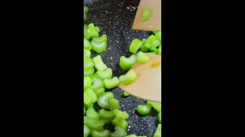 Vertical shot Close-up of celery stalks frying in a hot pan. Slow motion footage Stock Footage 302638112