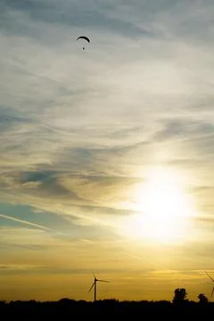 Vertical shot of a cloudy sunset sky with a silhouette of a paraglider Stock Photos