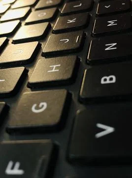 A vertical shot of a computer keyboard detail with screen light reflected on  Stockfoto's
