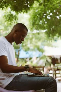 Vertical shot of concentrated modern multiracial man work on laptop, typing Stock Photos