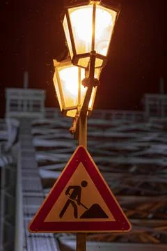 Vertical shot of a construction work sign on a lamp pole Stock Photos