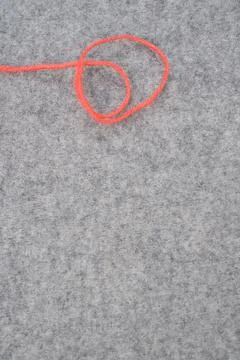 A vertical shot of a curvy red string on a gray wool background with copy spa Stock Photos