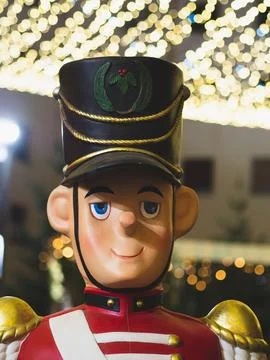Vertical shot of a cute nutcracker decoration under Christmas lights in a city Stock Photos