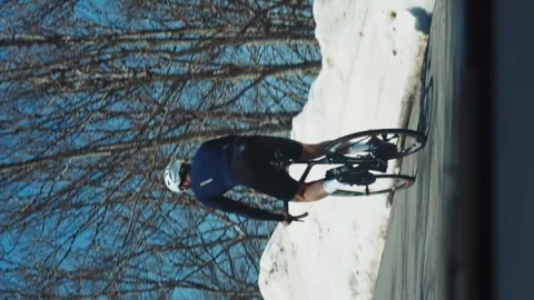 Vertical shot cyclist competes on a mountain snowy road among high mountains Stock Footage 245003051