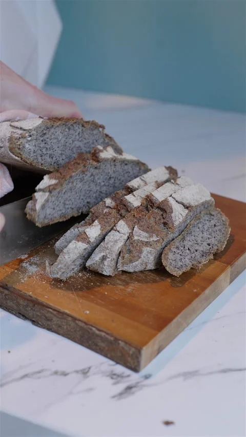 Vertical shot of dark rye wheat bread cutting on wood block 動画素材 223691042