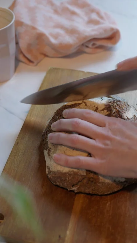 Vertical shot of dark rye wheat bread cutting on wood block 動画素材 223691410