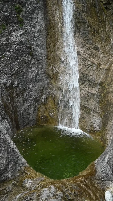 Vertical shot of the deep pond of a waterfall with green water, slow motion Stock Footage 260887897