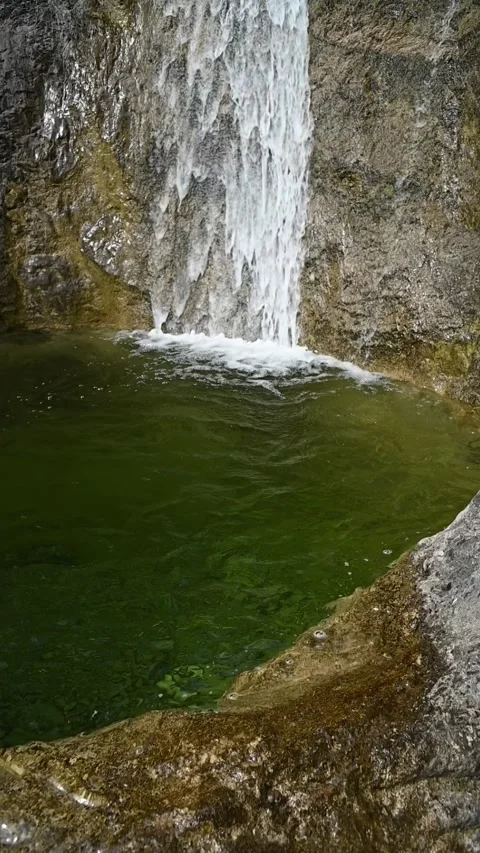 Vertical shot of the deep pond of a waterfall with green water, slow motion Stock-Footage 260888133