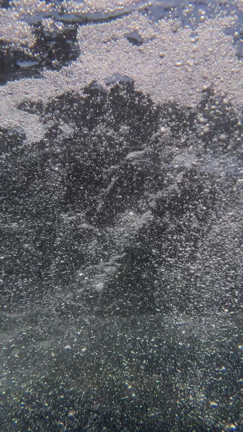 Vertical shot of a dense stream of underwater air bubbles moving through seawate Stock Footage 345101765