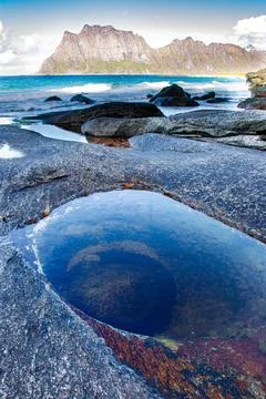 Vertical shot of the Devil Eye surrounded by rocky hills in Lofoten, Norway Stock Photos