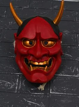 Vertical shot of a devil mask on a black brick wall - Halloween concept 스톡 사진