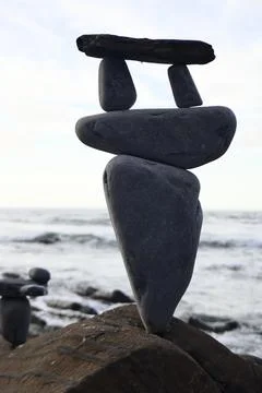 A vertical shot of different size and shape stones on each other with the sea Stock Photos