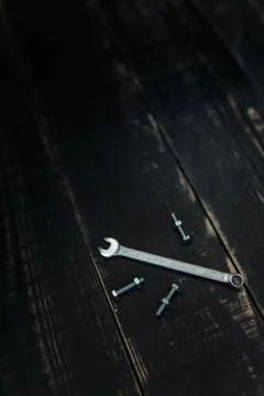 Vertical shot of a double sided key, some nuts and bolts on black background Stock-Fotos