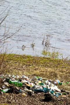 Vertical shot of dumped rubbish by the water at a park in Bezid, Romania Stock Photos