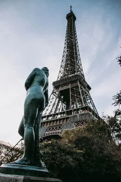 Vertical shot of the Eiffel Tower surrounded by greenery in the daylight in Pari 스톡 사진