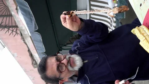 Vertical shot of an elderly man with glasses holding a meatless trout fish with Stock Footage 160089894