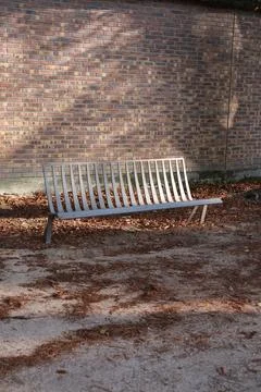 Vertical shot of an empty bench in the Garden of Plants in Paris, France Stock Photos
