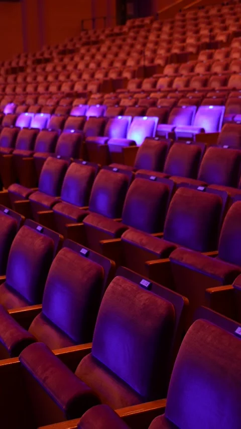 Vertical shot of empty theater seats with red and purple lighting Stock Footage 346347293