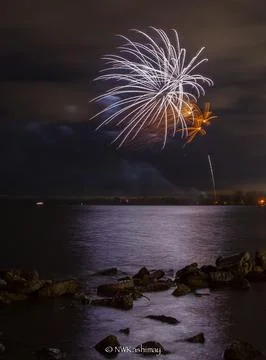 Vertical shot of exploding colorful fireworks in a night sky over a lake Stock Photos