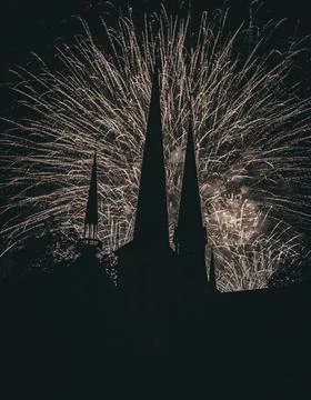 Vertical shot of exploding fireworks behind a tower silhouette Foto stock