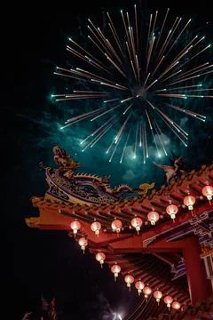 Vertical shot of exploding fireworks over a Chinese building roof Stock Photos
