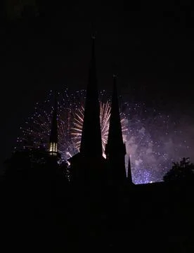 Vertical shot of exploding purple fireworks behind a building silhouette Stock Photos