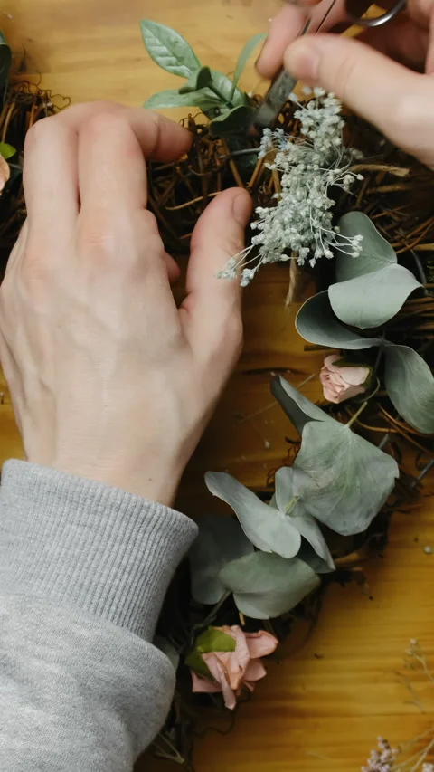 Vertical shot. Female hands making floral wreath. DIY spring home decor. Stock Footage 253678813