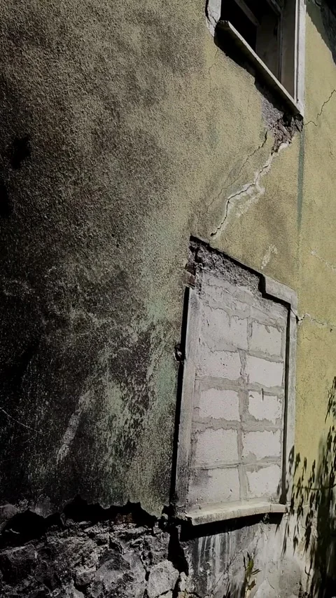 Vertical shot of a fire-damaged abandoned building wall with a bricked-up wi 動画素材 328402433
